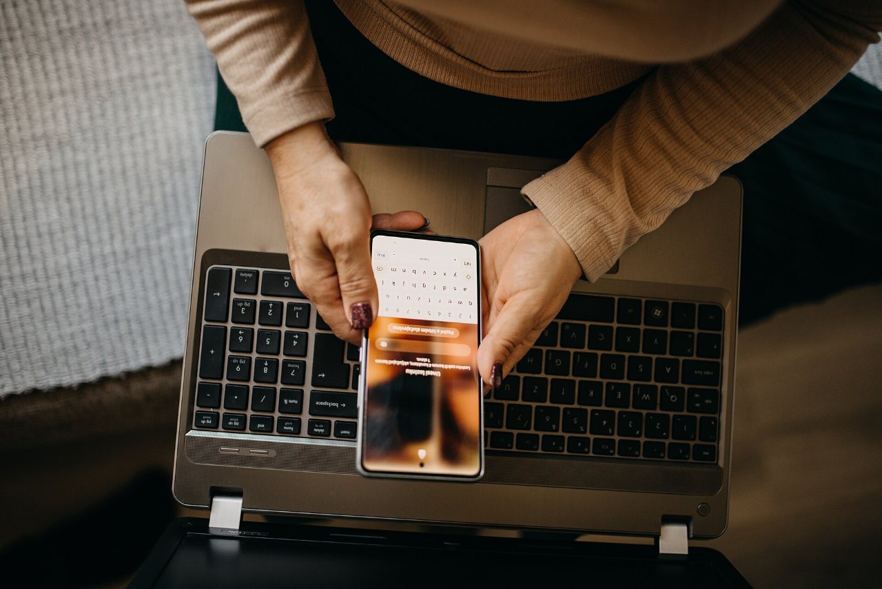Middle-aged woman using a smartphone with laptop