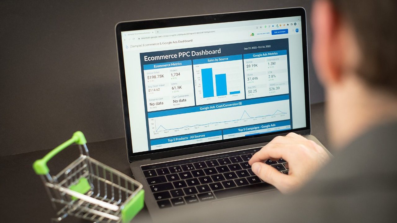 Laptop showing an online shop checkout next to a card machine and shopping bags