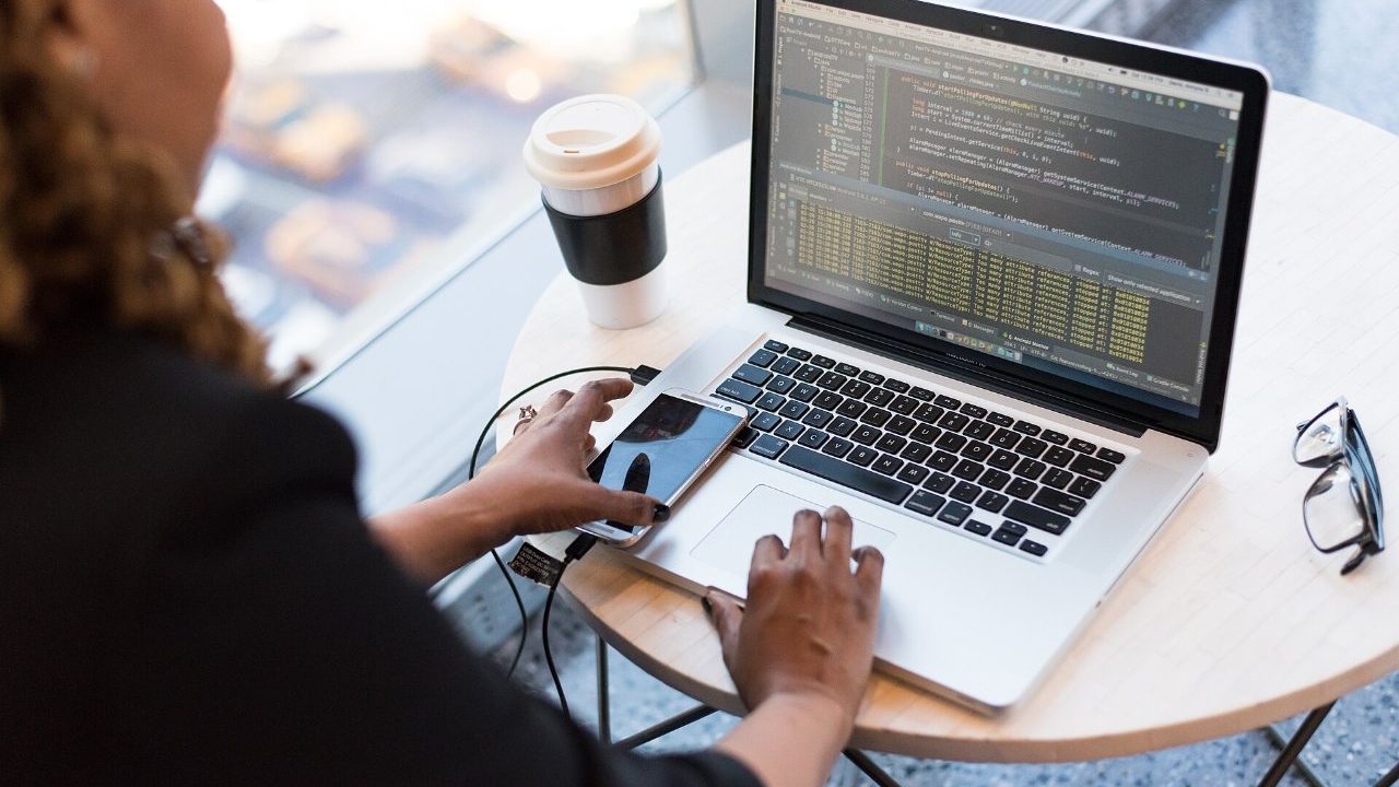 Software engineer reviewing and restructuring legacy source code across two monitors